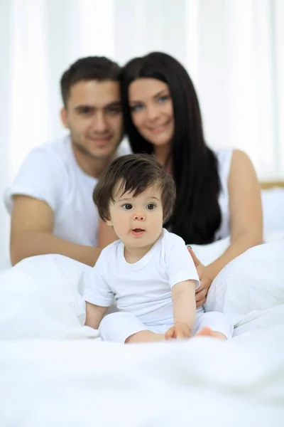 Lyckliga paret och son sitter i sängen — Stockfoto