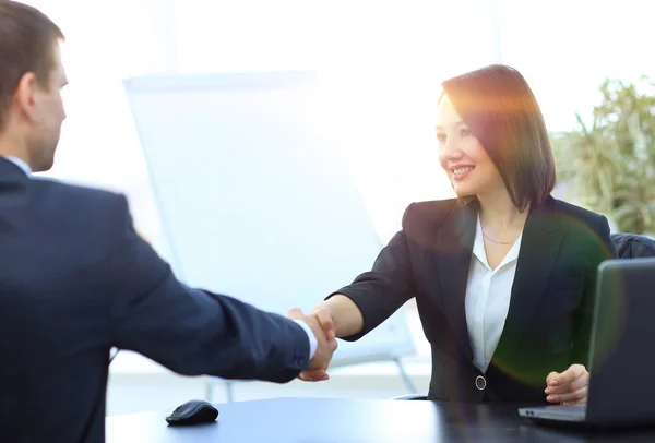 Mulher de negócios apertando as mãos com um parceiro de negócios sobre uma mesa — Fotografia de Stock