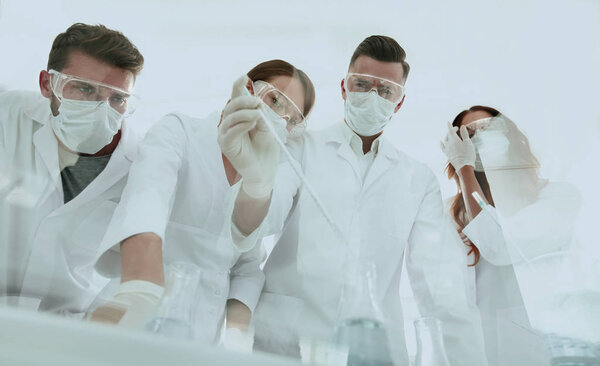 учёные, работающие с пробирками и микроскопом в лаборатории
