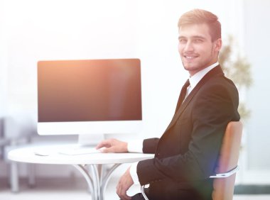 Masada oturan ve kameraya bakarak başarılı iş adamı.