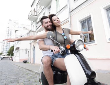 Güzel genç bir çift bir scooter sürme sırasında gülümsüyor