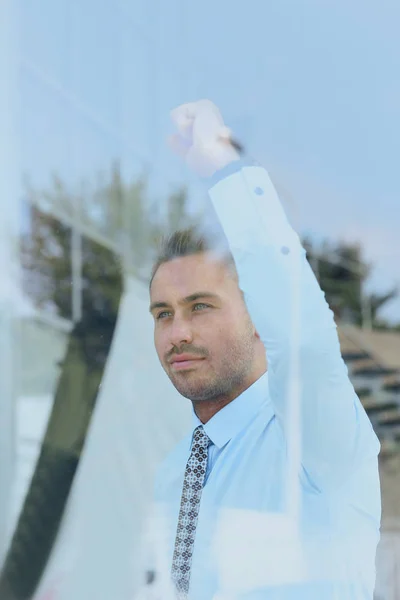 Vue de derrière glass.confident homme d'affaires regardant par la fenêtre de son bureau — Photo