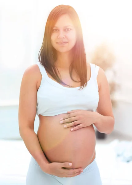 Portret van jonge zwangere vrouw op een lichte achtergrond. — Stockfoto