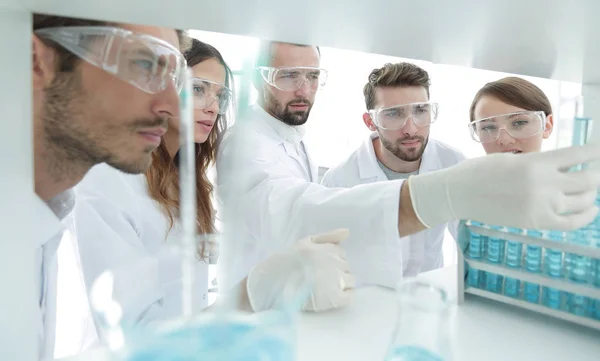 A imagem de fundo é um grupo de microbiologistas que estudam o líquido no tubo de vidro . — Fotografia de Stock