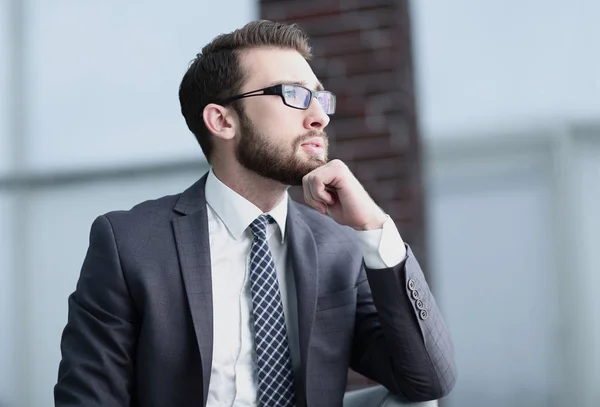 Handsome businessman thinks, sitting on couch in his office — Stock Photo, Image