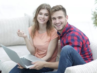 Dizüstü bilgisayarı olan iki öğrenci kanepede oturuyor.