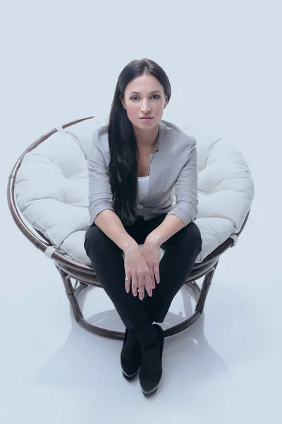 Современная молодая женщина, сидящая в круглом уютном мягком кресле — стоковое фото