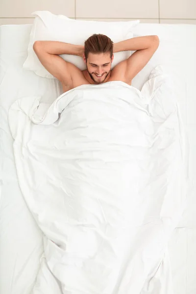 Jeune homme couché sur un matelas confortable . — Photo