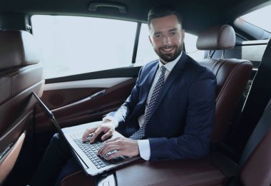 Arabanın içinde otururken dizüstü klavye üzerinde işadamı