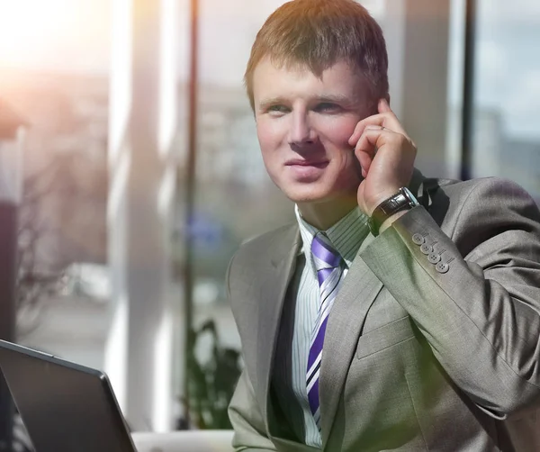 Aantrekkelijke Europese man praten over de telefoon terwijl het gebruiken van laptop. — Stockfoto