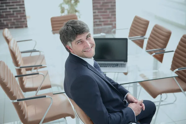 Lächelnder Manager sitzt am Schreibtisch im Besprechungsraum. — Stockfoto