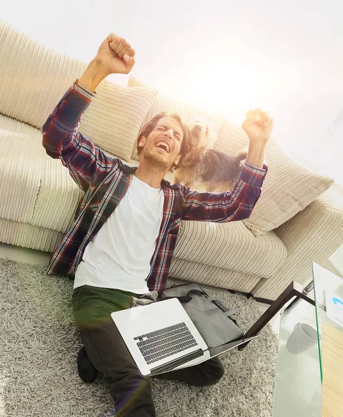 Chico feliz con el ordenador portátil jubiloso en la amplia sala de estar . —  Fotos de Stock