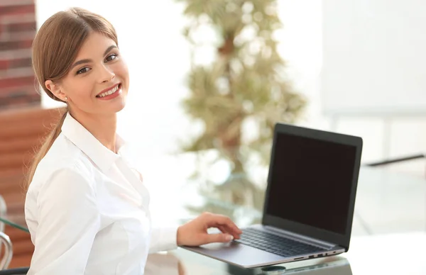 Joven mujer de negocios sentada en su escritorio en una oficina, trabajando en una computadora portátil —  Fotos de Stock