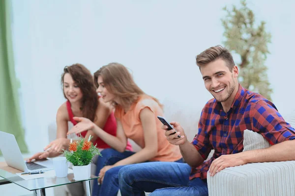 Moderner Kerl mit Smartphone und seinen Freunden auf der Couch — Stockfoto