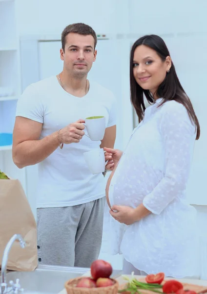 Karı ve onun hamile eşi kakao içmeye, mutfakta ayakta. — Stok fotoğraf