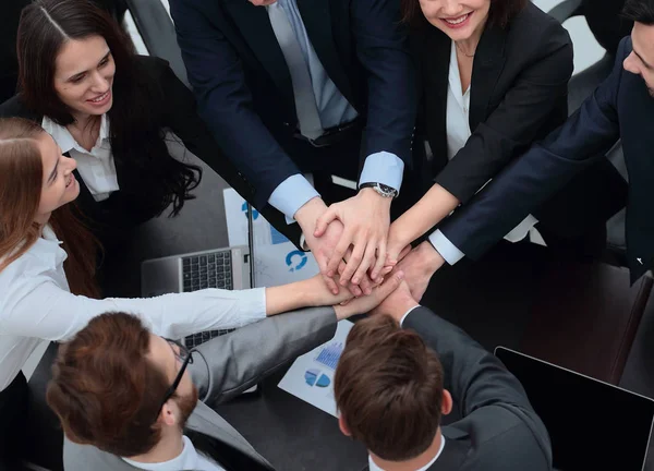 Equipo de negocios con las manos juntas en el escritorio — Foto de Stock