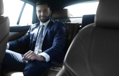 bir arabanın arka koltuğunda oturan işadamı