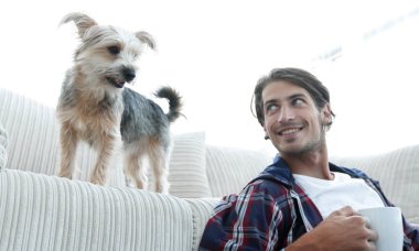 genç adam kanepede yakın katta oturan çay içiyor.