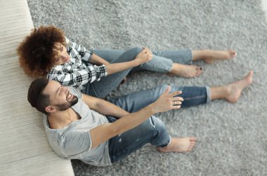 yeni bir oturma odasında bir halı üzerinde oturan yeni evli çift