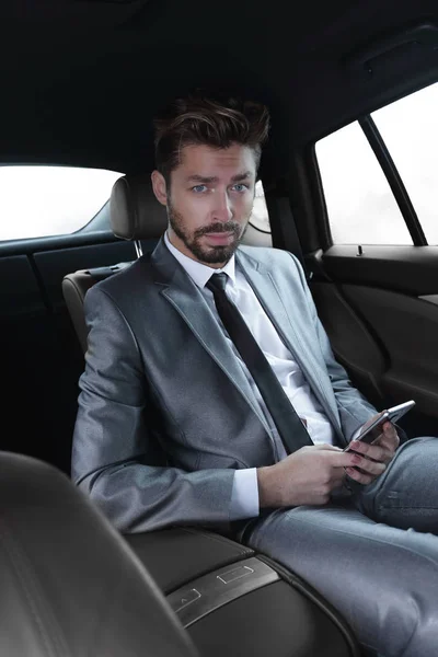 Férfi öltöny, ülő-ban autót üzenetek olvasása és írása a smartphone — Stock Fotó