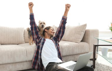 mutlu genç adam köpeğiyle oturma odasında exults