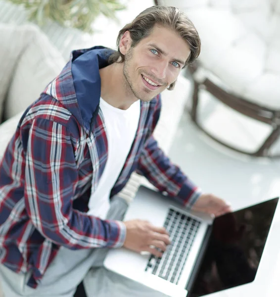 Młody człowiek pracuje na laptopie i patrząc na kamery. od góry — Zdjęcie stockowe