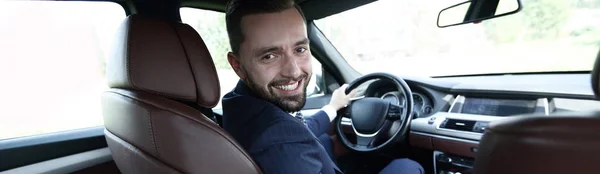 Homem de sucesso sentado ao volante de um carro de prestígio — Fotografia de Stock