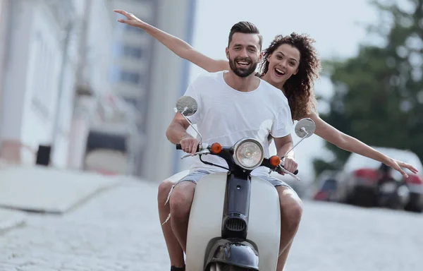 Feliz joven pareja montando un scooter en la ciudad en un día soleado —  Fotos de Stock