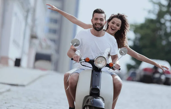 Happy young couple riding a scooter in the city on a sunny day — Stock Photo, Image