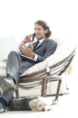 onun evinde sandalyede oturan smartphone cep telefonu ile konuşurken işadamı