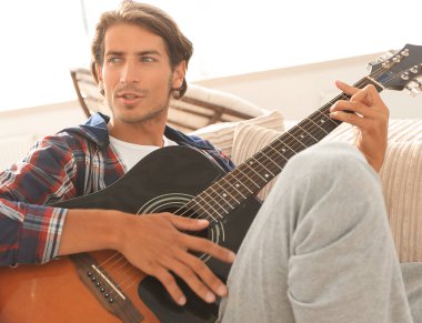 oturma odasında kanepede oturup gitar ile Modern adam.