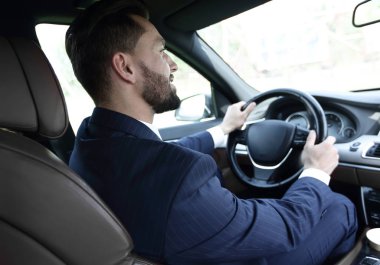 işadamı direksiyonda arabasında oturur ve yola görünüyor