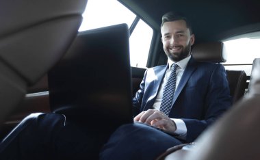 Arabada otururken diz üstü üzerinde çalışan iş adamı