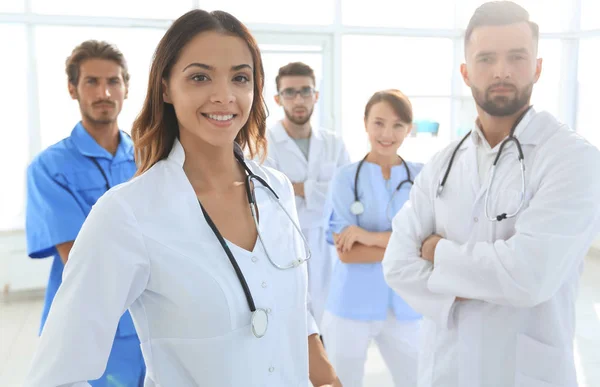 Attraente medico femminile con stetoscopio medico di fronte al gruppo medico — Foto Stock