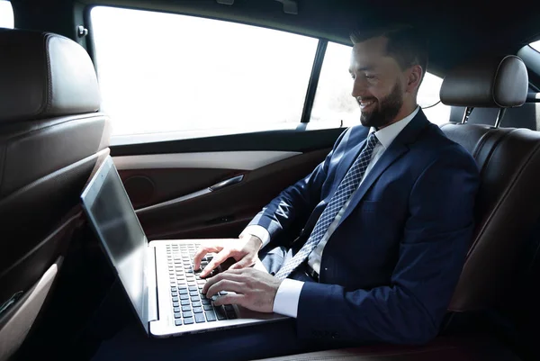 使用笔记本电脑坐在车里的商人 — 图库照片