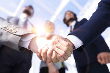 İş ortaklarının el sıkışması ön planda.