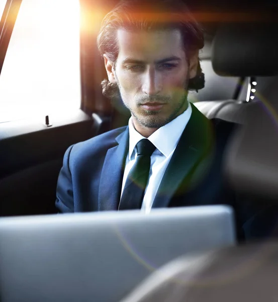 Hombre trabajando en el ordenador portátil mientras está sentado en el coche — Foto de Stock