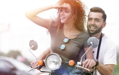 Güzel genç bir çift bir scooter sürme sırasında gülümsüyor