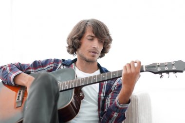 Yakışıklı adam evde kanepede gitar çalmaya