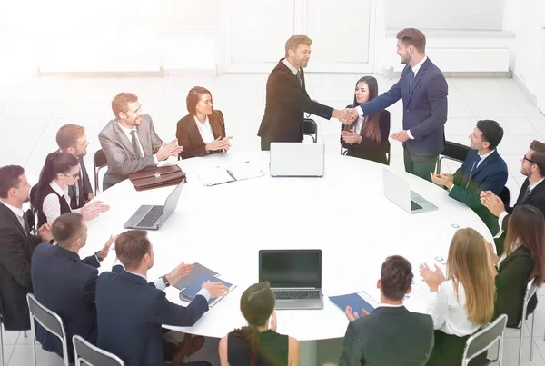 Geschäftspartner geben sich bei den Gesprächen am runden Tisch die Hand — Stockfoto