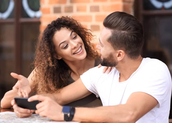 Happy älskande par som med en smartphone som sitter i terrass — Stockfoto