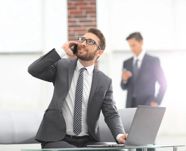 Confident young man talking on phone in office — Stock Photo, Image