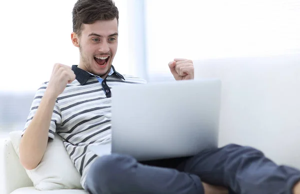 Hombre feliz con el ordenador portátil sentado en el sofá — Foto de Stock