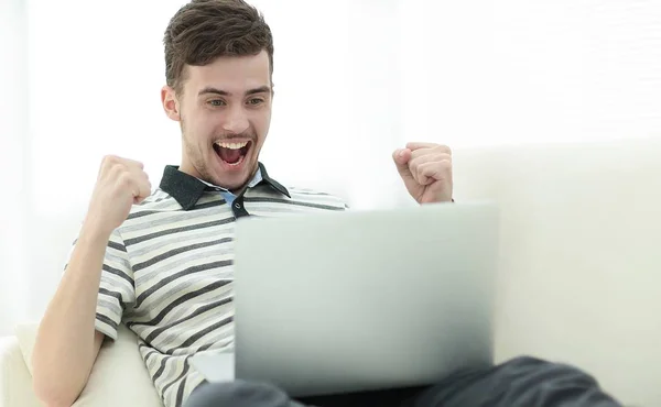 Hombre feliz con el ordenador portátil sentado en el sofá — Foto de Stock