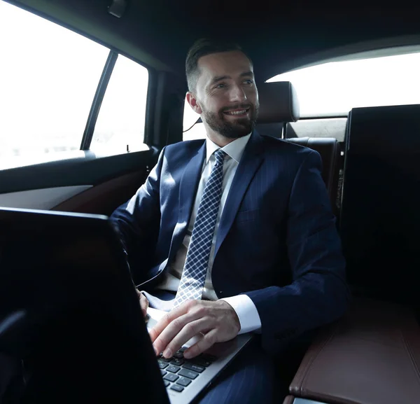 Mann mit Laptop auf dem Rücksitz im Auto — Stockfoto