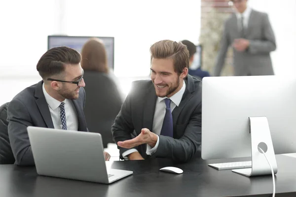 Compañeros alegres se divierten sentados en el escritorio con computadoras portátiles — Foto de Stock