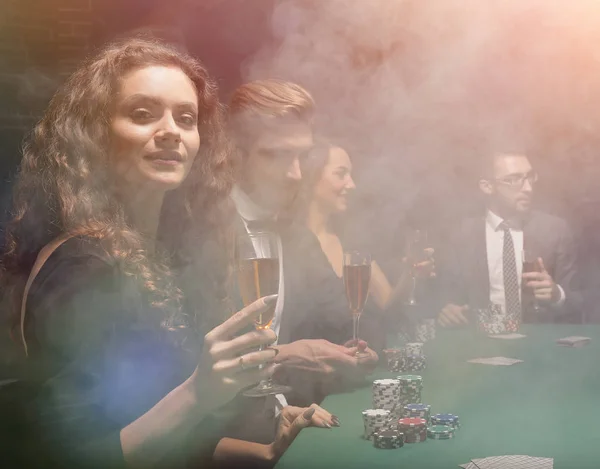 Groep vrienden zitten op de speeltafel in casino — Stockfoto