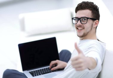 açık belgili tanımlık laptop önünde oturan ve gösterilen modern genç yukarı başparmak