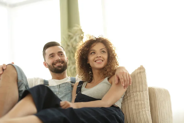 Young couple in work clothes sitting on couch — Stock Photo, Image