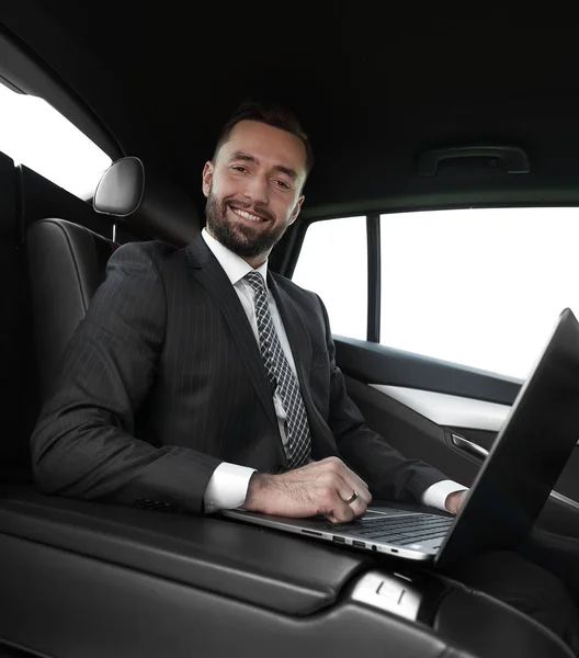 Uomo di successo che lavora con il computer portatile seduto in auto — Foto Stock